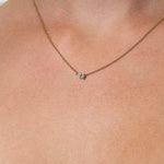 Necklace with a lab grown diamond pendant on a person's neck against a neutral background