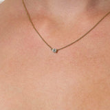 Necklace with a lab grown diamond pendant on a person's neck against a neutral background