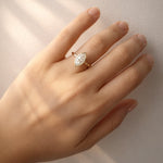 Gold ring with a lab created diamond on a hand against a white background