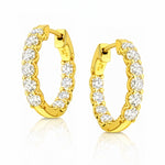 A pair of yellow gold hoop earrings with clear lab grown diamonds on a white background