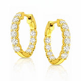 A pair of yellow gold hoop earrings with clear lab grown diamonds on a white background