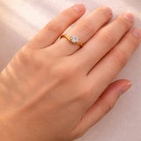 Gold ring with a pear cut lab grown diamond on a hand against a neutral background