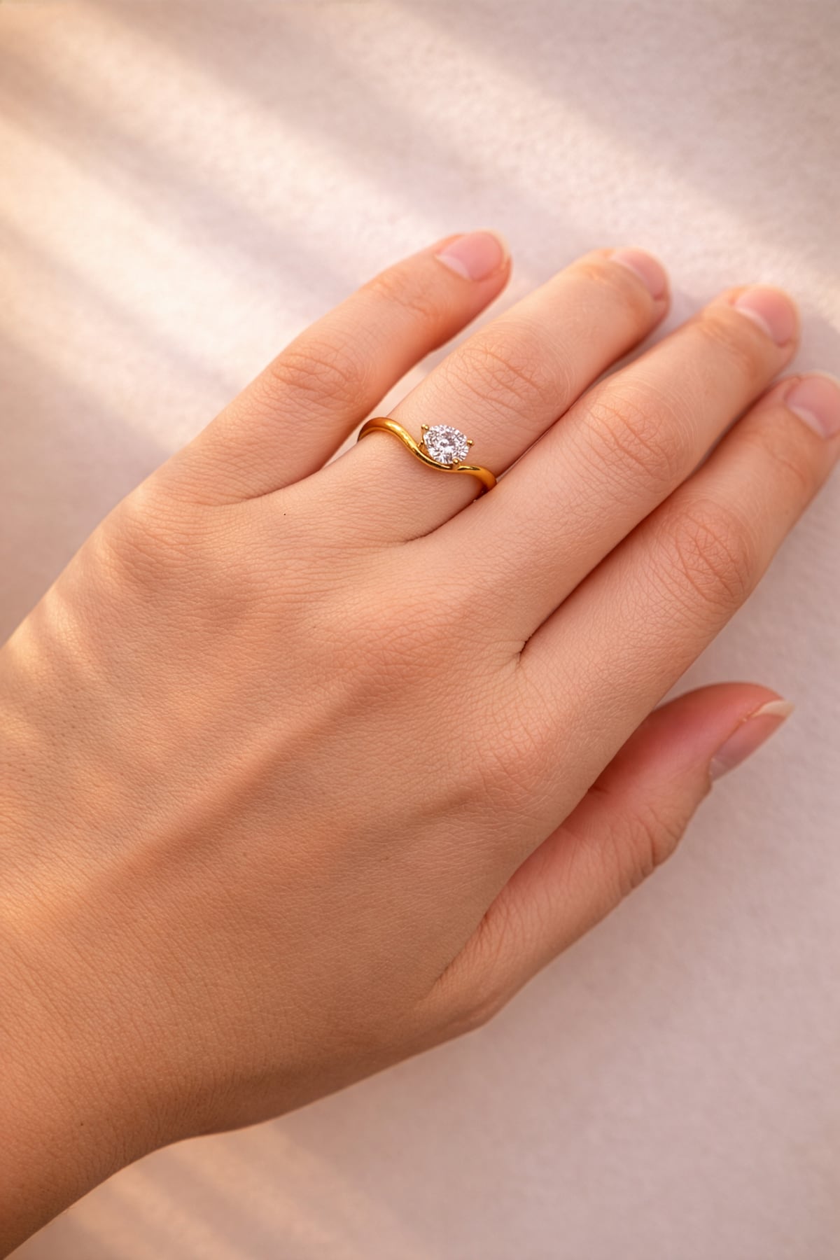 Gold ring with a pear cut lab grown diamond on a hand against a neutral background