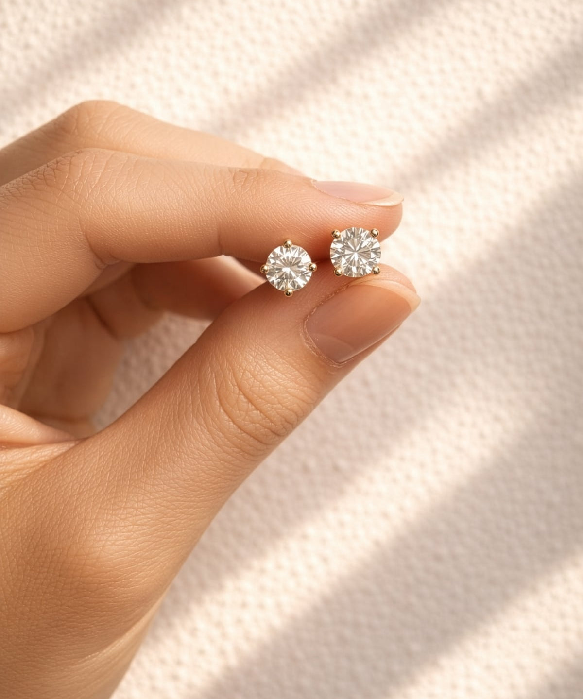 Hand holding a pair of lab diamond stud earrings against a soft background at LeGassick, Gold Coast, Australia.