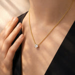 Gold necklace with a lab grown diamond pendant worn by a person against a neutral background