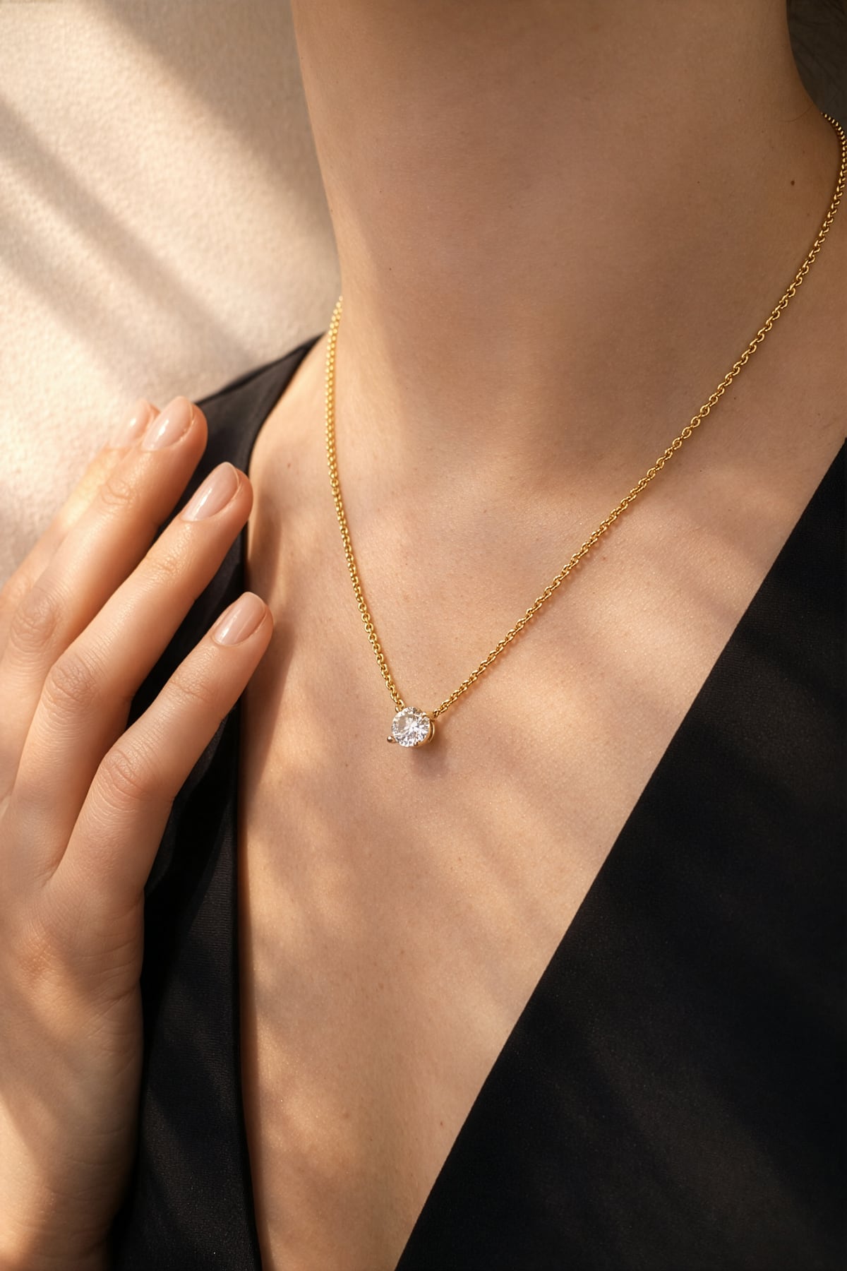 Gold necklace with a lab grown diamond pendant worn by a person against a neutral background