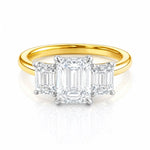 Gold ring with three emerald-cut lab diamonds on a white background