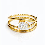 Gold ring with a lab grown pear diamond on a white background