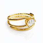 Gold ring with a lab grown pear diamond on a white background