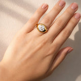 Hand wearing a gold ring with a lab grown diamond on a neutral background