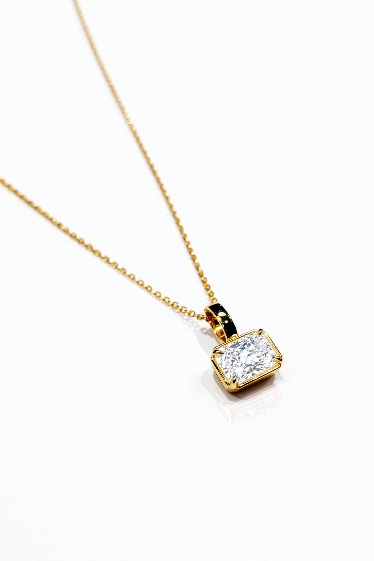 Gold necklace with a lab grown diamond pendant on a white background