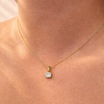 Gold necklace with a square lab grown diamond pendant on a person's neck