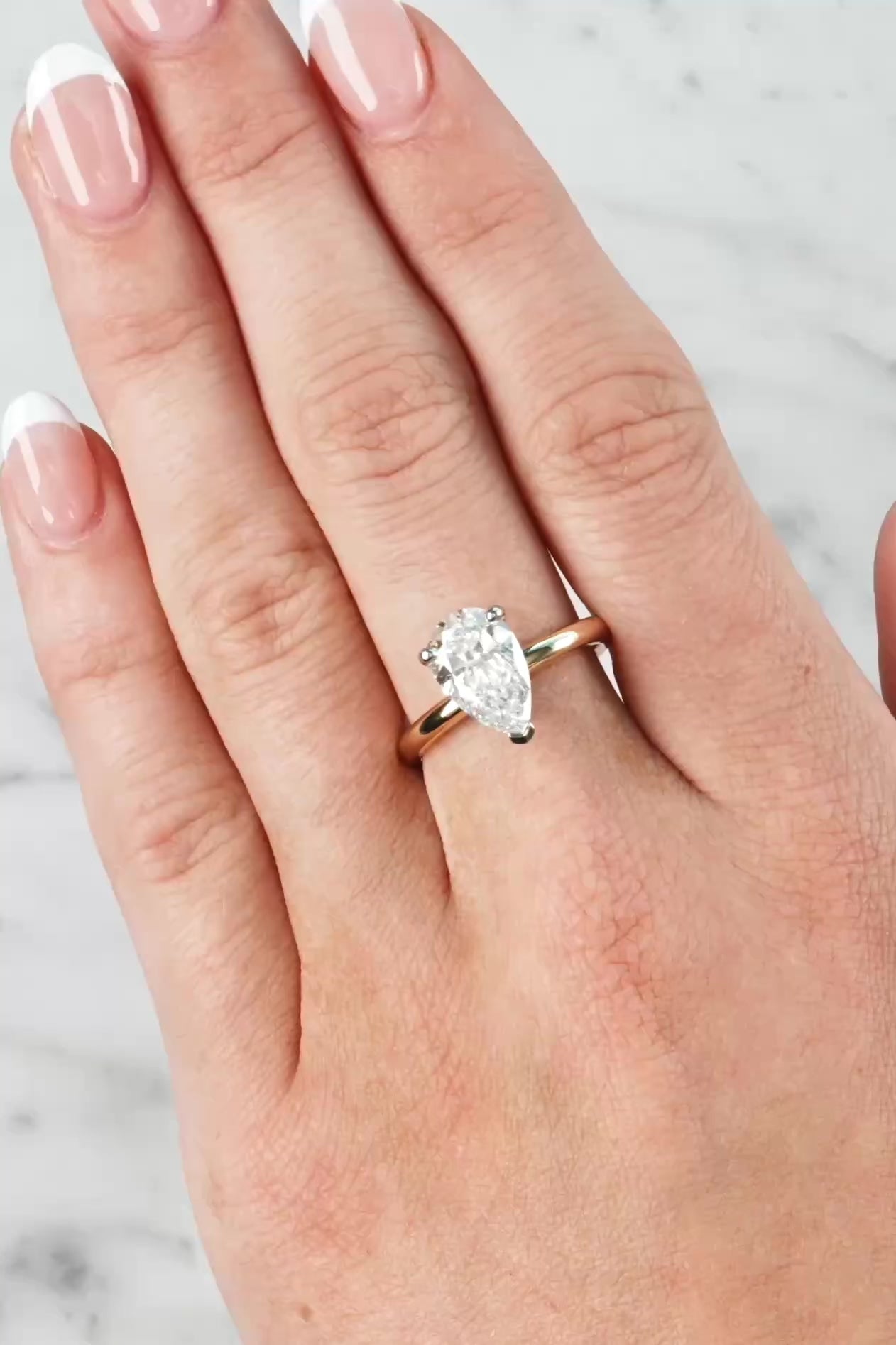 Gold ring with a lab grown diamond on a hand against a neutral background at LeGassick.