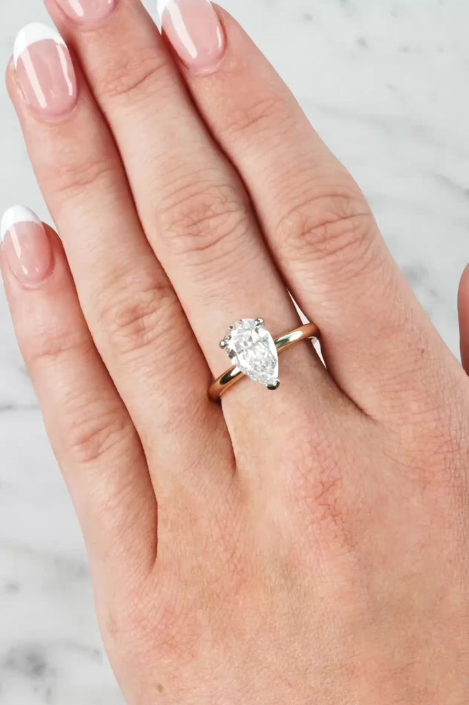 Gold ring with a lab grown diamond on a hand against a neutral background at LeGassick.