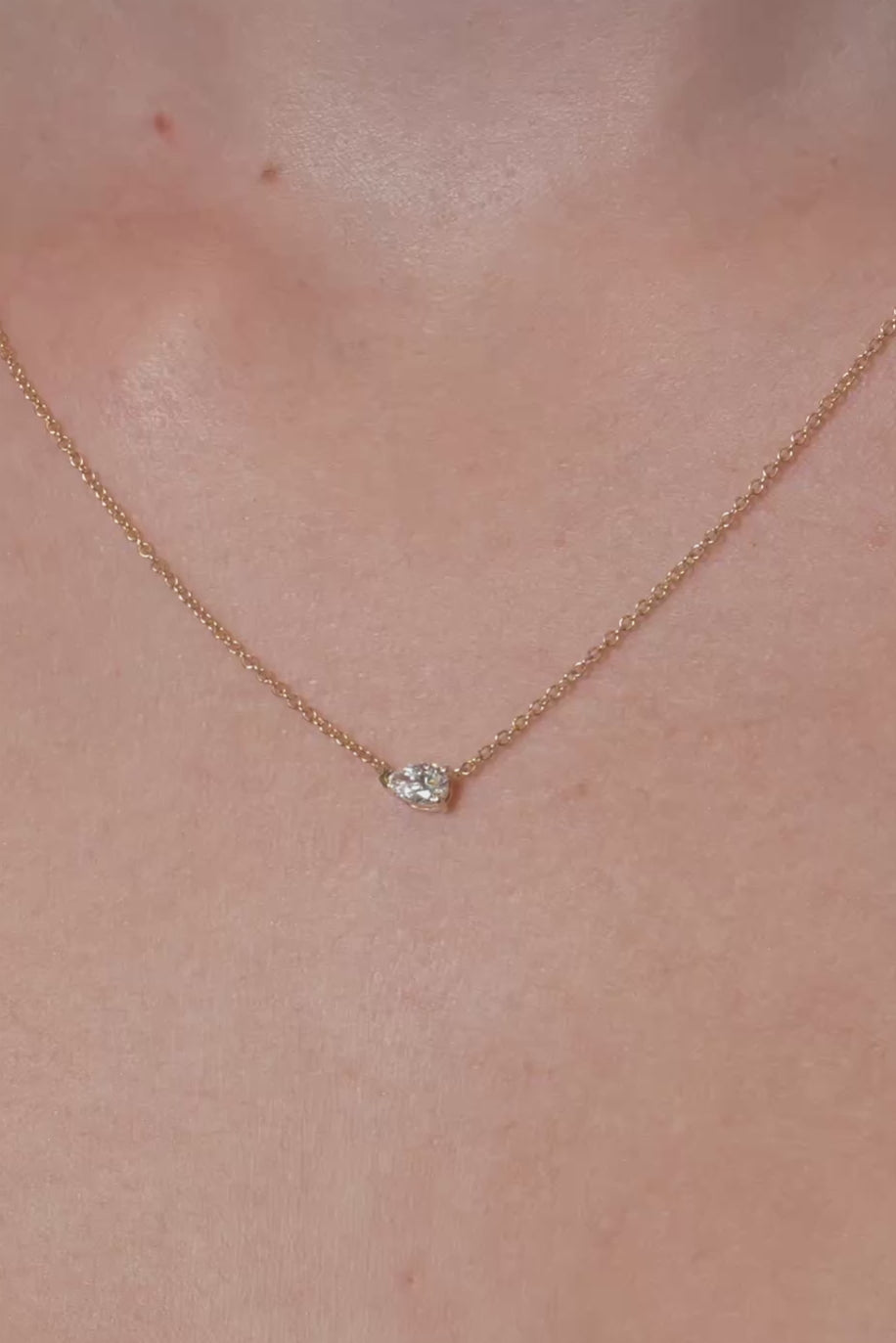 Necklace with a lab grown diamond pendant on a person's neck against a neutral background