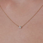 Necklace with a lab grown diamond pendant on a person's neck against a neutral background